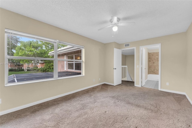 unfurnished bedroom with baseboards, visible vents, ensuite bath, a textured ceiling, and carpet flooring