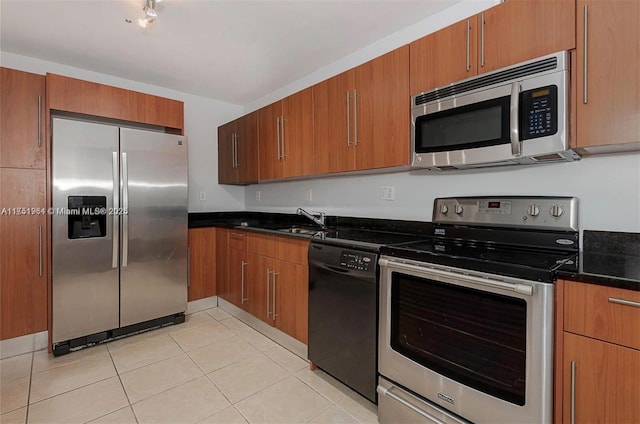 kitchen with light tile patterned floors, brown cabinets, appliances with stainless steel finishes, and a sink