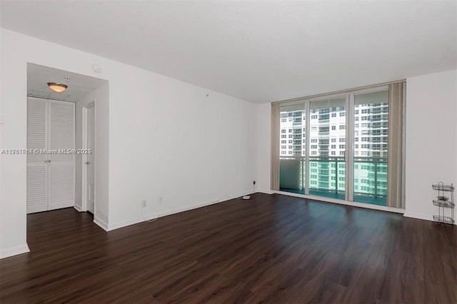 unfurnished room with baseboards, dark wood-style flooring, and floor to ceiling windows