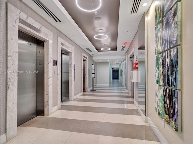 corridor with tile patterned floors, a tray ceiling, elevator, and visible vents