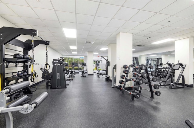 workout area with visible vents, a paneled ceiling, and baseboards