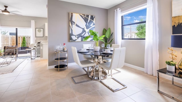 dining room with light tile patterned floors, baseboards, a ceiling fan, and a healthy amount of sunlight