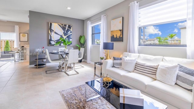 living area with a wealth of natural light, baseboards, and light tile patterned floors