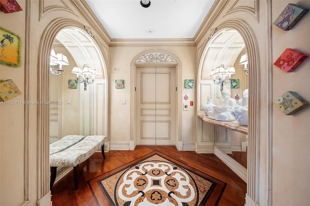 foyer with ornamental molding, arched walkways, baseboards, and wood finished floors