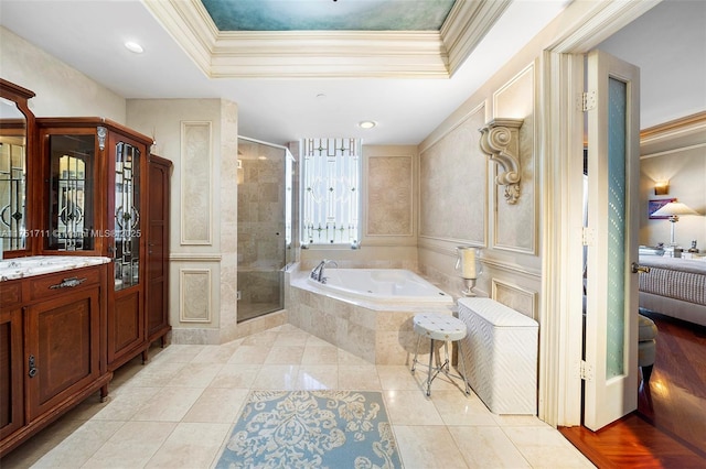 full bathroom with ornamental molding, a tray ceiling, and a decorative wall