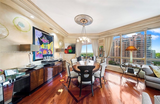 dining room featuring ornamental molding, a city view, a notable chandelier, and wood finished floors