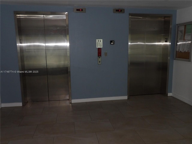 interior space featuring elevator, dark tile patterned floors, and baseboards