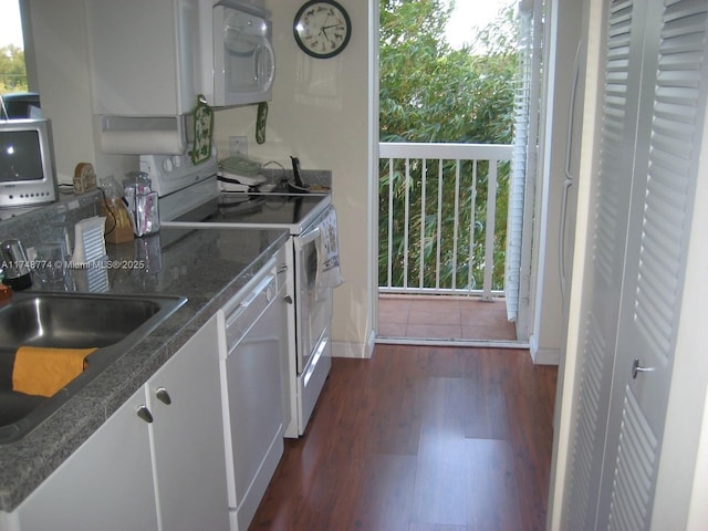 kitchen with white appliances, dark wood finished floors, dark stone countertops, white cabinetry, and a sink