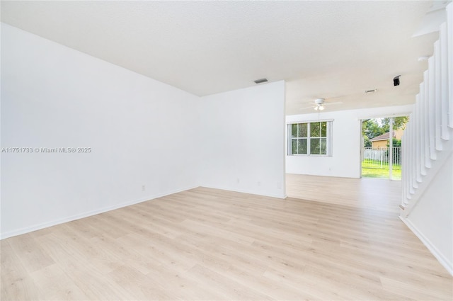 spare room featuring baseboards, light wood finished floors, ceiling fan, and visible vents