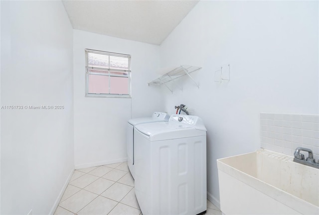 laundry room featuring laundry area, light tile patterned flooring, a sink, washer and dryer, and baseboards