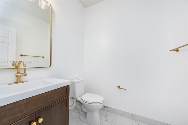 bathroom with toilet, vanity, and marble finish floor