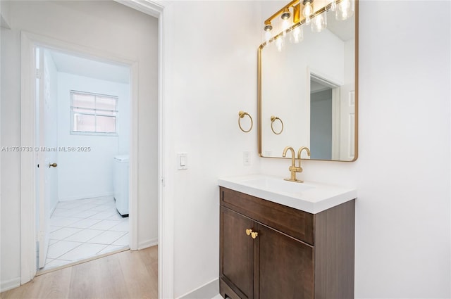 bathroom with washer / clothes dryer, vanity, and baseboards