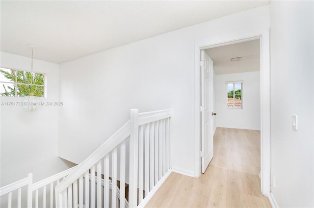 hallway with baseboards, an inviting chandelier, an upstairs landing, visible vents, and light wood finished floors