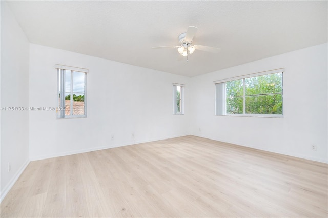 empty room featuring baseboards, light wood-type flooring, and a ceiling fan