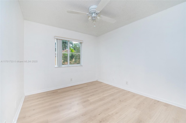 spare room with light wood-style flooring, baseboards, and a textured ceiling