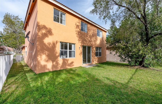 rear view of property with a yard, a fenced backyard, and stucco siding