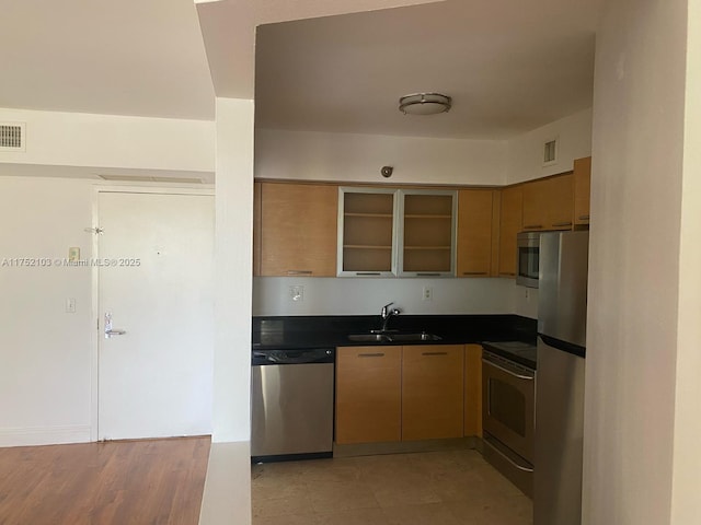 kitchen featuring appliances with stainless steel finishes, dark countertops, visible vents, and a sink