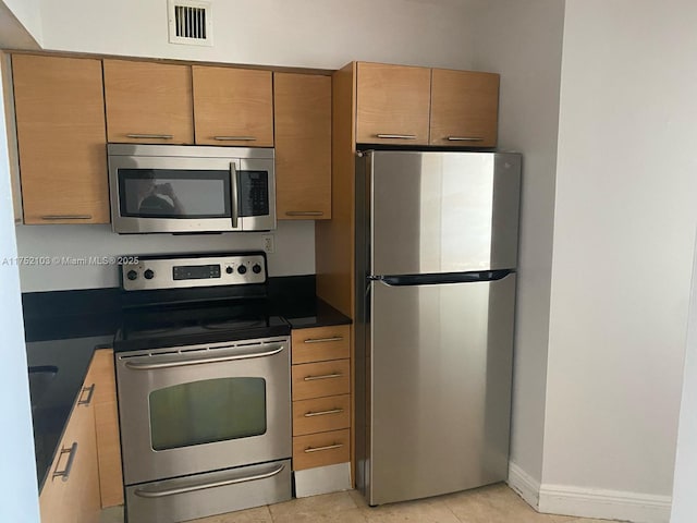 3300 NE 191st St Unit 416, Aventura, FL 33180 - kitchen with stainless steel appliances, dark countertops, visible vents, light tile patterned flooring, and baseboards