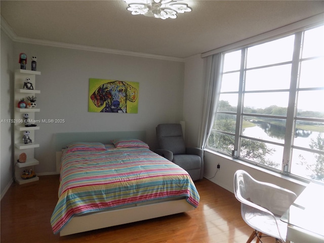 bedroom featuring ornamental molding, a water view, and wood finished floors