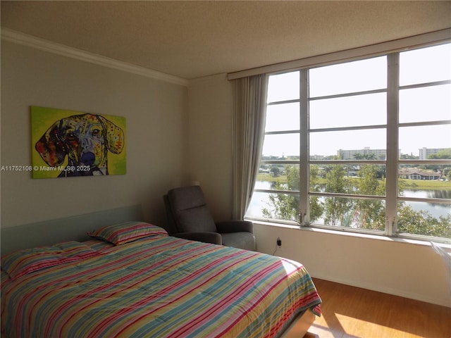 bedroom with a water view, crown molding, and wood finished floors