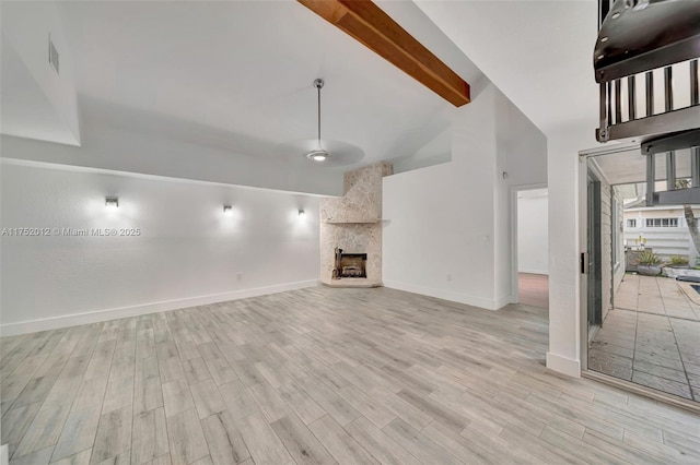 unfurnished living room with beam ceiling, light wood-style flooring, a large fireplace, high vaulted ceiling, and baseboards