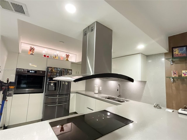 kitchen featuring a sink, visible vents, white cabinetry, black appliances, and island exhaust hood