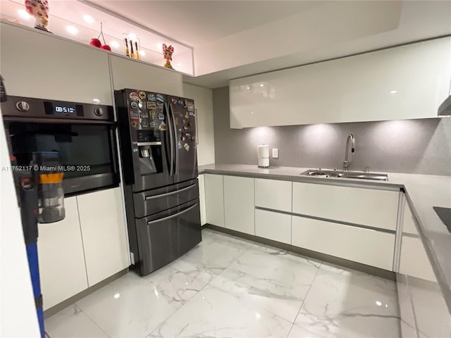 kitchen with marble finish floor, fridge with ice dispenser, white cabinetry, a sink, and black oven