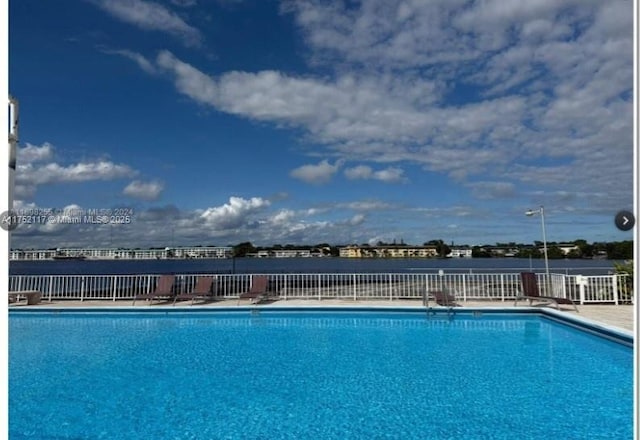 community pool featuring a water view and fence