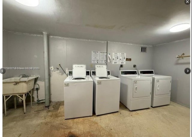 community laundry room featuring light floors, visible vents, a sink, and independent washer and dryer