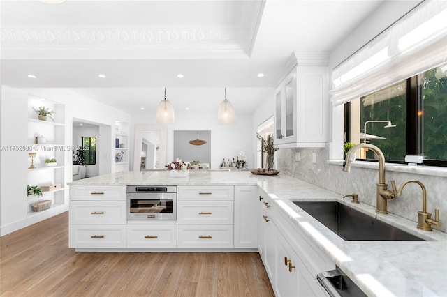 kitchen with light stone counters, a sink, stainless steel oven, and white cabinets