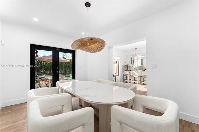 dining area with light wood-style floors, recessed lighting, french doors, and baseboards