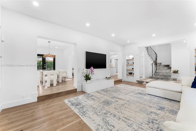 living area featuring light wood-style flooring, recessed lighting, stairway, and baseboards