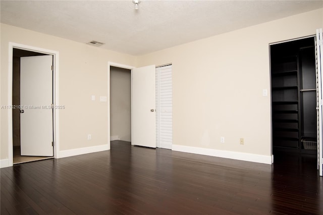 unfurnished bedroom with dark wood-type flooring, visible vents, and baseboards