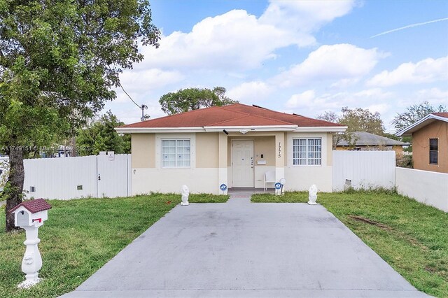 bungalow with a gate, stucco siding, a front yard, and fence