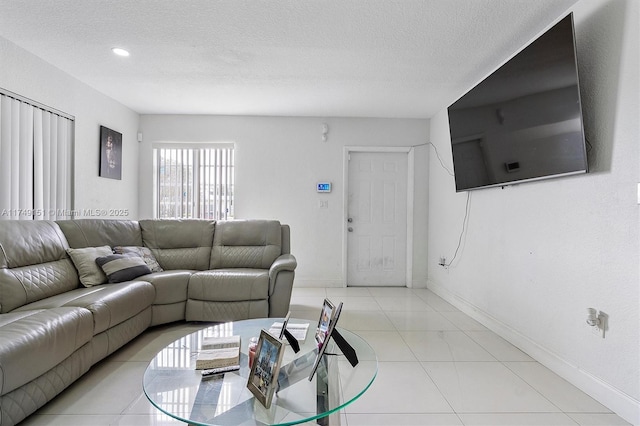 living area with light tile patterned floors, baseboards, and a textured ceiling