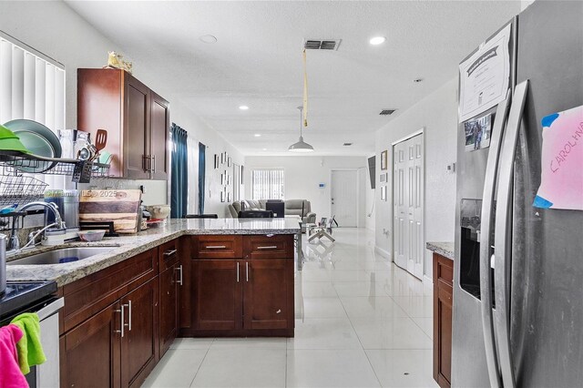 kitchen with visible vents, stainless steel refrigerator with ice dispenser, a sink, open floor plan, and a peninsula