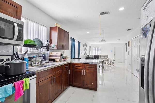 kitchen featuring visible vents, open floor plan, a peninsula, stainless steel appliances, and a sink