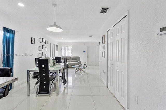 dining room with visible vents, a textured ceiling, light tile patterned floors, baseboards, and a textured wall