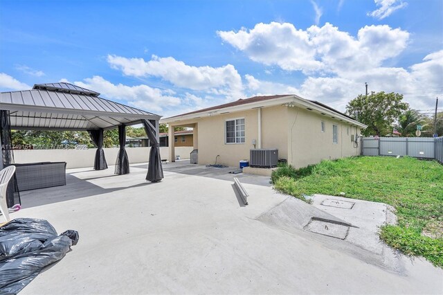 rear view of house with a patio, a fenced backyard, central AC, stucco siding, and a gazebo