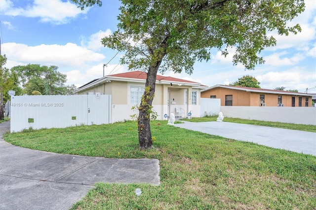 view of front facade featuring stucco siding, concrete driveway, a front yard, and fence