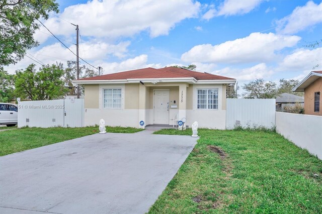 view of front of property featuring a gate, stucco siding, a front lawn, and fence