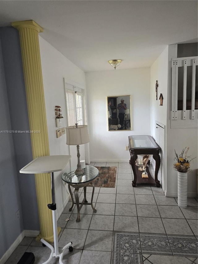 living area with ornate columns, tile patterned flooring, and baseboards