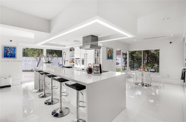 kitchen with a breakfast bar, a sink, light countertops, a large island, and modern cabinets