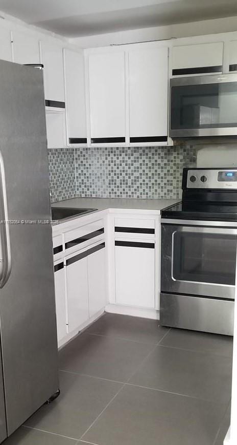 kitchen featuring appliances with stainless steel finishes, white cabinets, and dark tile patterned flooring