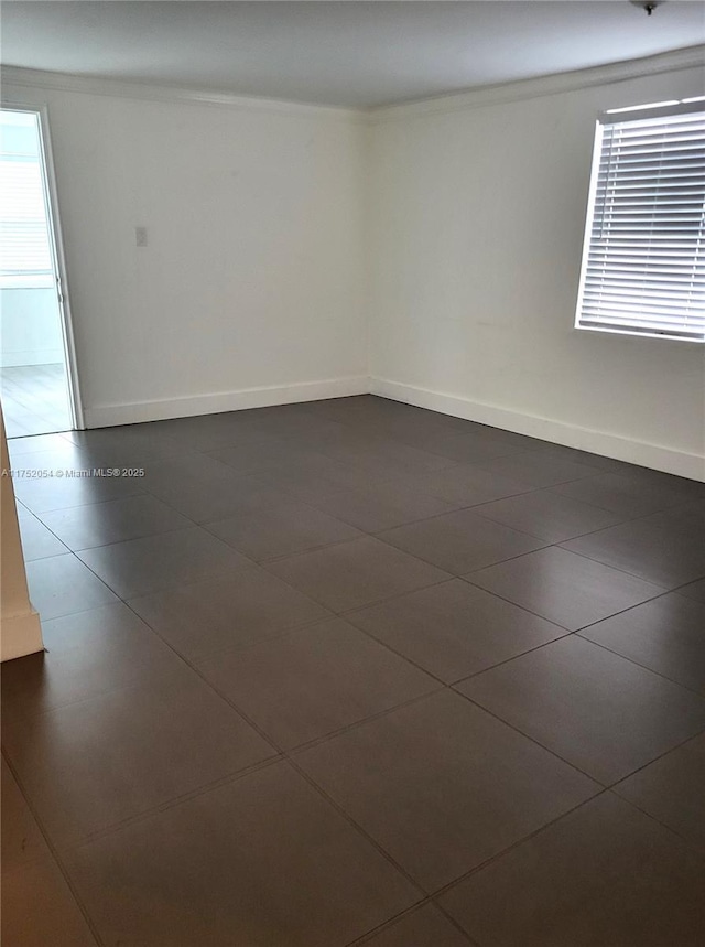 unfurnished room featuring crown molding, dark tile patterned floors, and baseboards