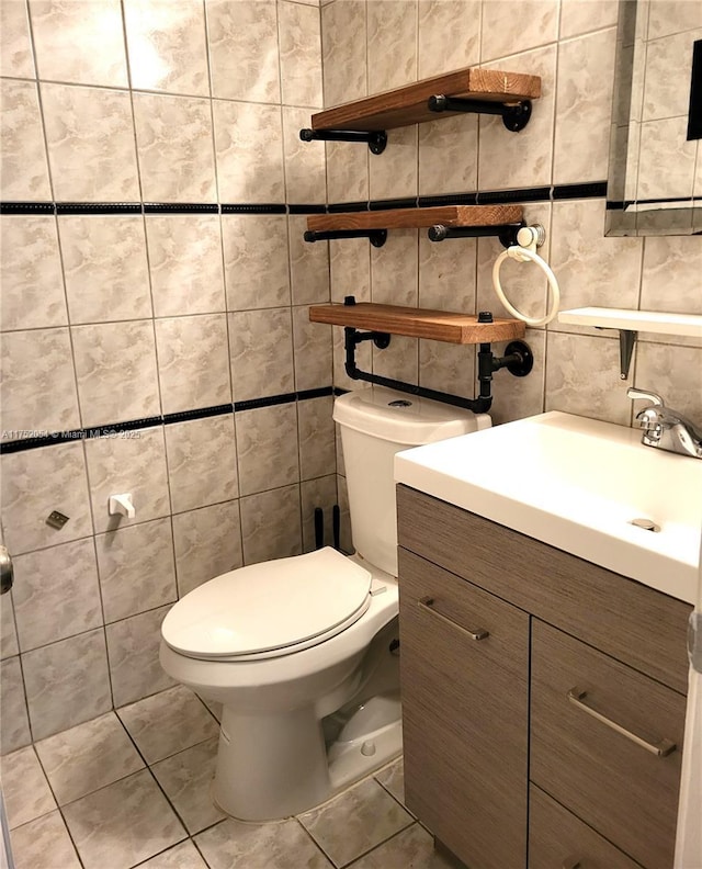 bathroom featuring tile patterned floors, vanity, toilet, and tile walls