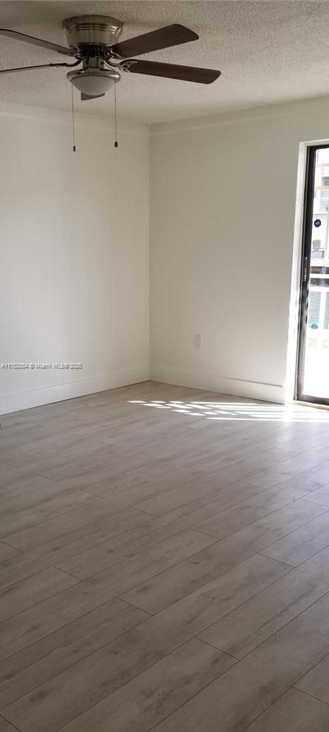 empty room featuring a ceiling fan, a textured ceiling, and wood finished floors