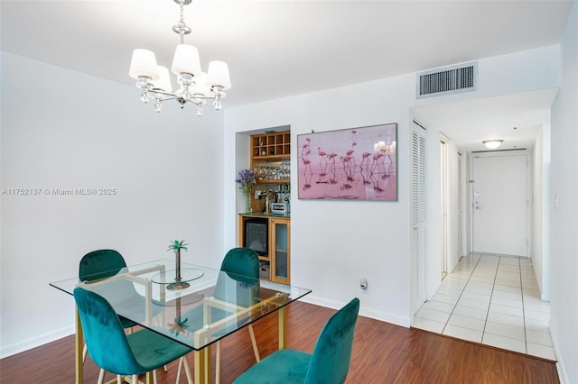 home office featuring visible vents, a notable chandelier, baseboards, and wood finished floors