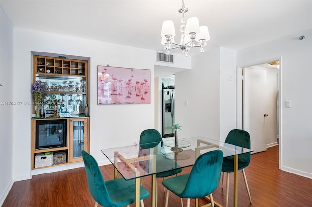 dining room with dark wood-type flooring, a chandelier, visible vents, and baseboards