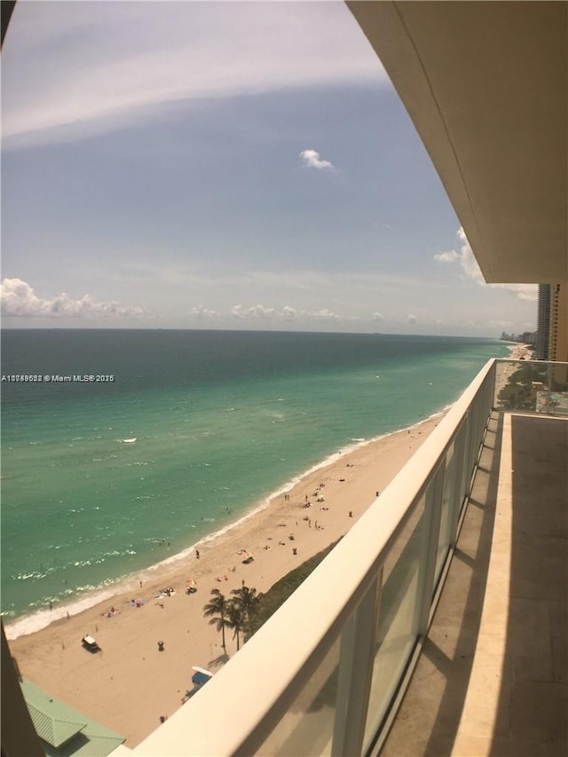 balcony with a water view and a view of the beach